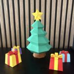 Sapin vert à étages avec étoile jaune et cadeaux colorés, sculpture en papier 3D