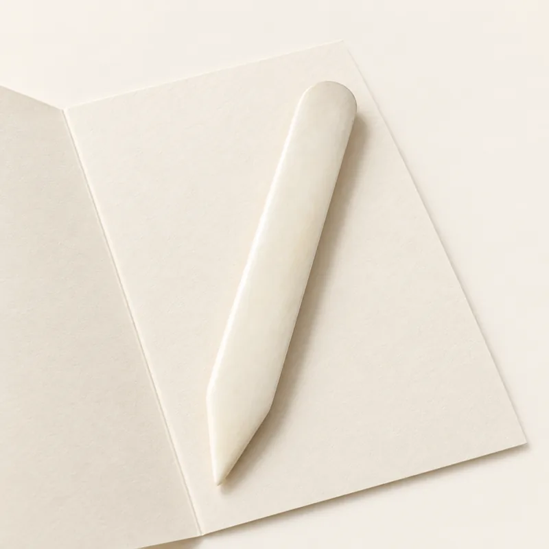 Plioir en os sur une feuille de carte